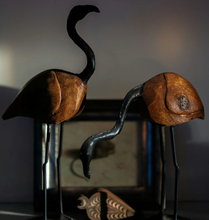 A couple of wooden birds standing next to each other